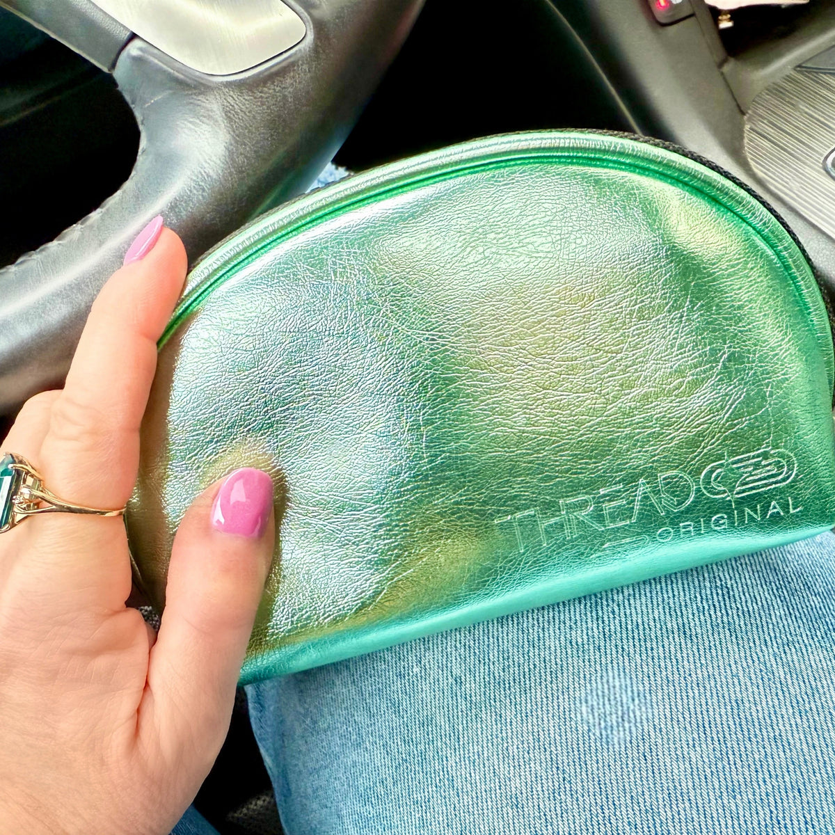 Hand holding Mint Luna LED makeup bag inside a car.