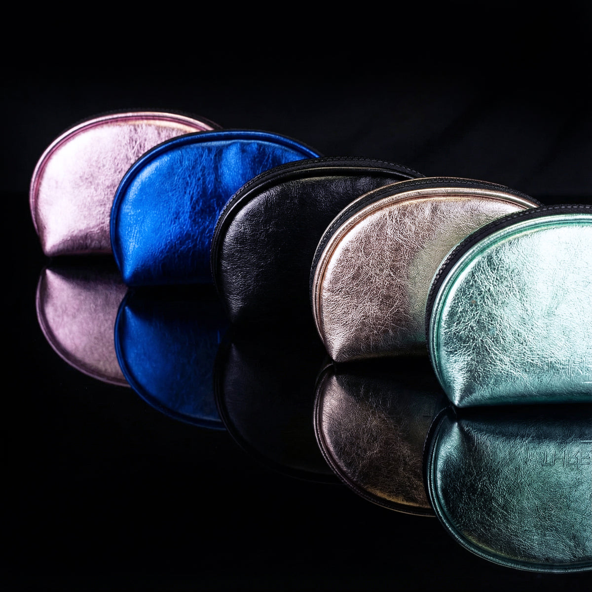 Luna LED makeup bags in Mint, Fizz, Onyx, Ocean and Pink displayed on a reflective black background.