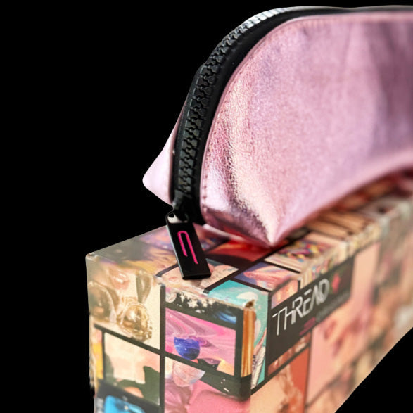 Side view of the Lyra compact makeup bag in metallic Pink, showing the zipper detail while resting on a Thread Original box.
